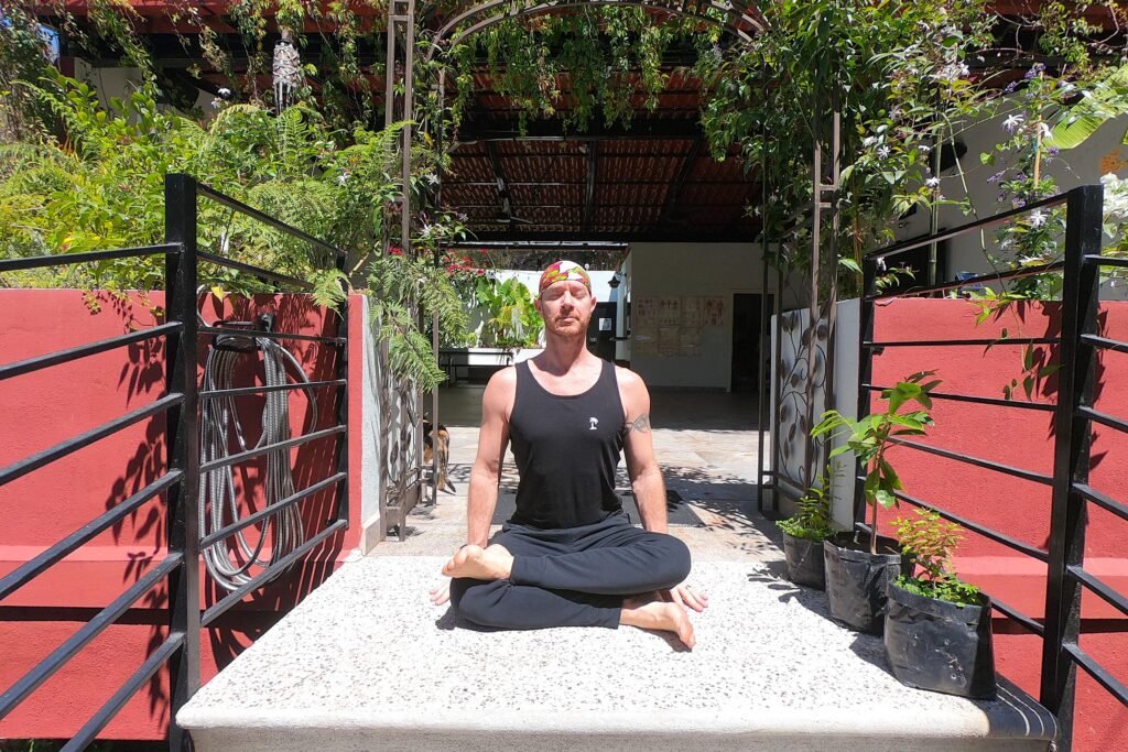 Yoga Teacher/Trainer, Jai Salsbery E-RYT500 performing Fire Log Pose (Agnistambhasana) on the steps to the Vallarta Breeze Yoga Puerto Vallarta Yoga Studio